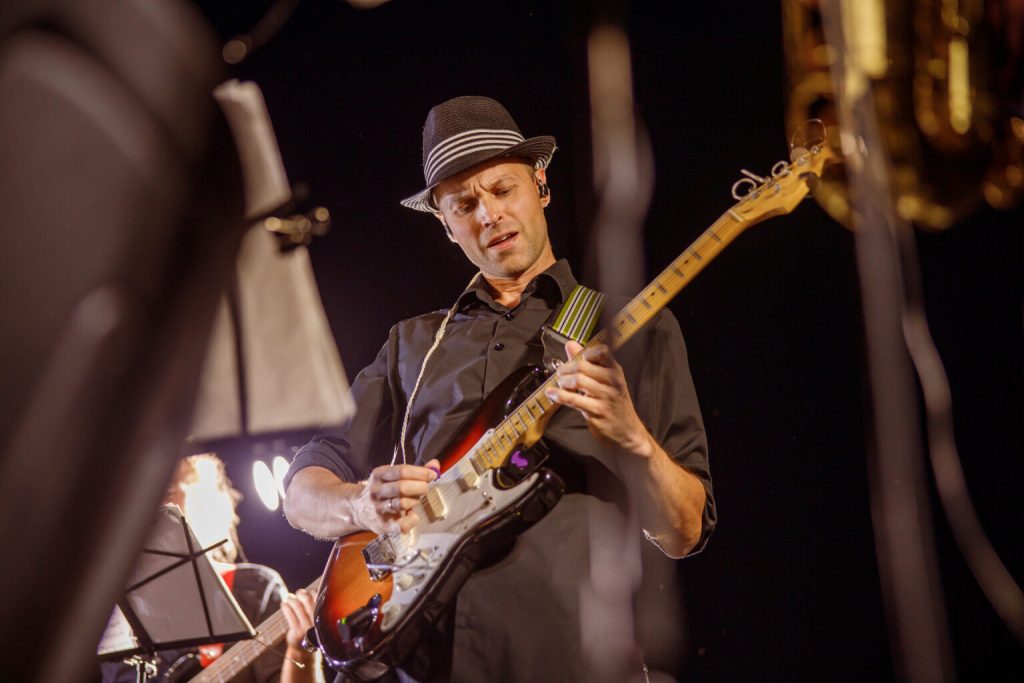 Guitarist in a hat playing an electric guitar on stage at night