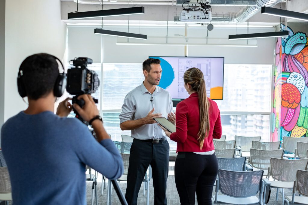 A presenter with a tablet being filmed for a corporate video