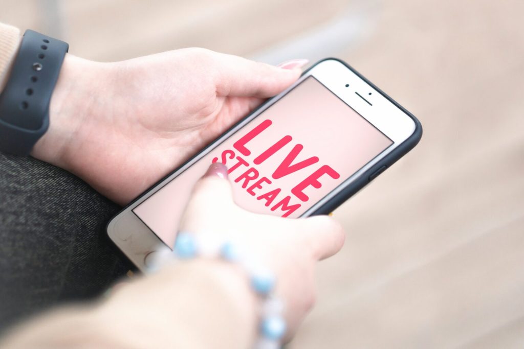 Hands holding a phone showing a live stream screen